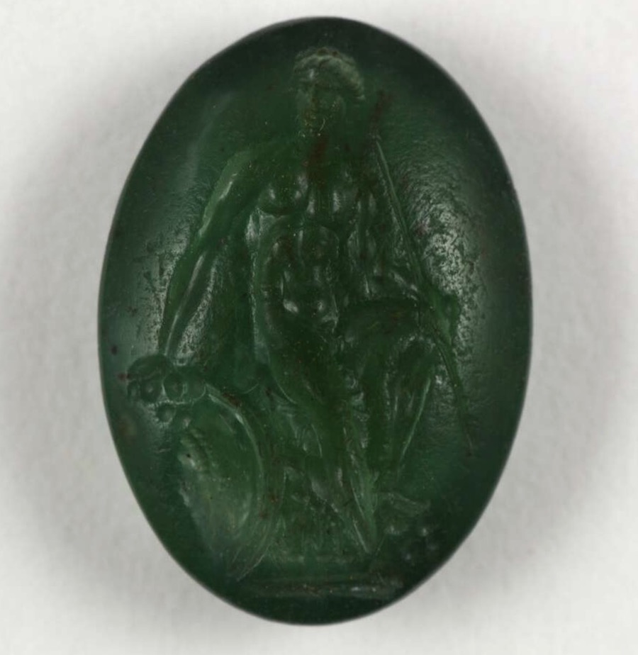 Oval plasma intaglio: young warrior on a rock, holding a spear, with a shield beside him.