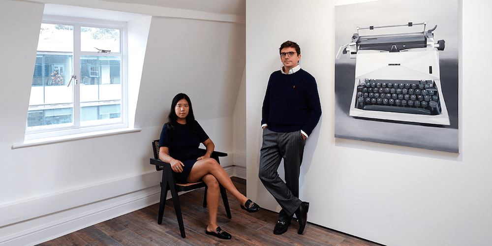 I Just Gotta Do It – Alexandra BaraitserNearly twenty years after her last solo exhibition with a commercial gallery, Alexandra Baraitser returns with I Just Gotta Do It at Tiderip’s new space on Percy Street. Recently relocated from Battersea, the gallery begins its next chapter by bringing Baraitser’s long-standing practice back into public view.When asked about her artistic practice, Baraitser said, “I’ve just got to do it, and I sort of feel better after I have.” This instinctive desire has sustained her practice over three decades of painting. Born in Cape Town, South Africa, in 1971, Baraitser has followed an unusual path as a professional artist. Shortly after graduating with an MA in Painting from Chelsea College of Art, she exhibited at the Barbican Centre and in the John Moores Painting Prize in 1996, received the Abbey Scholarship in Painting at the British School at Rome in 1996 and 1997, and was named a finalist in the NatWest Art Prize in 1998.Following The Future Past, her 2007 solo exhibition with Mark Jason Gallery, Baraitser continued painting at a distance from the commercial art world, allowing her practice to evolve alongside her everyday life. Now, she revisits a subject that once defined her work: designed objects. Bringing new perspectives and techniques to a familiar theme, she re-examines the shifting relationships between design, photography and painting.I Just Gotta Do It opens with a room of typewriters, a subject that came to Baraitser in the past year. Though no longer household staples, typewriters remain rooted in personal and generational memory. Their practical function may have diminished, but their cultural significance remains widely recognised. By depicting objects associated with communication with the outside world, Baraitser invites audiences to understand the world through her lived experience.Tiderip founders Marjorier Ding and Louis Jacquier, with Typeface (2026) by Alexandra Baraitser.Baraitser’s creative process has remained largely consistent over the past three decades. She begins with found images of designed objects, often sourced from old magazines or catalogues, and develops her paintings from them. She now uses computer software more extensively to research and alter these images, giving the works a surreal, retro-futurist quality. The typewriter paintings are based on existing models: Typeface depicts the British Olivetti 82 Vintage Manual Typewriter, while Typing Test draws on the Olivetti Studio 45 Manual Typewriter.Compared with the precision of her earlier work, Baraitser’s brushstrokes are now looser, with parts of the paintings intentionally blurred. By subtly altering details such as the keys and labels, she shifts attention away from the typewriters’ function, transforming them into objects suspended between memory, image and painting. Her practice explores how painting can be reinvented, and how it relates to design and photography.The second room returns to Baraitser’s first recurring subject: designed chairs. It brings two recent works into conversation with an earlier piece. Bellini Side Chair 1 (2006), also shown in her last solo exhibition, hangs opposite Evolution of the Chair (2026) and Vignette (2026). In all three paintings, a single chair sits at the centre of the canvas, treated with a visual language reminiscent of monumental portraiture.The compositions reveal Baraitser’s enduring interest in design, while the palette shows how her work has changed. Like many of her earlier furniture paintings, Bellini Side Chair 1 uses a black-and-white gradient, with carefully modulated shades that create a sense of space and light. In her recent works, she uses brighter, richer colours. The arrangement of the paintings makes this shift especially visible.Eames and Co (2026) by Alexandra Baraitser.The exhibition concludes with three smaller works. In Eames and Co and New Orange, radiant, semi-translucent colours create a sense of lightness and warmth. Experimenting with colour allows Baraitser to bring a more personal feeling to the images. She has also begun exploring interior design. In Upstairs, Downstairs, a more complex structure and elaborate composition create a sense of mystery.At this stage of her life and career, Baraitser is increasingly comfortable taking risks. She experiments with the images she collects, pushing them further towards abstraction. Yet the instinct that has sustained her practice remains unchanged. Painting has continued through different periods of her life, sometimes within the commercial art world and sometimes at a distance from it. I Just Gotta Do It feels less like a return than a continuation: a practice that never really stopped, but has gathered new possibilities through time and experience.Exhibition preview by curator Yiran Zhu.I Just Gotta Do It7th October – 7th November 2026Tiderip17 Percy Street, London W1T 1DU